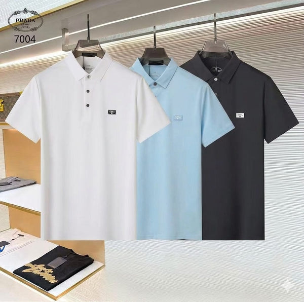 Three polo shirts in white, light blue, and black hanging on a rack with Prada branding.