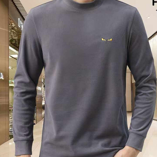 Person wearing a gray long-sleeve shirt with a small logo in a store setting, featuring Fendi branding.